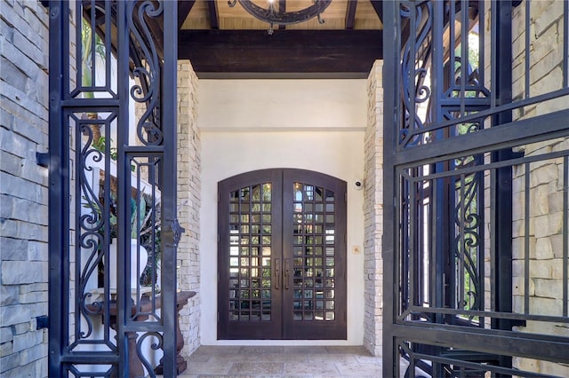 entryway featuring french doors, brick wall, and beam ceiling