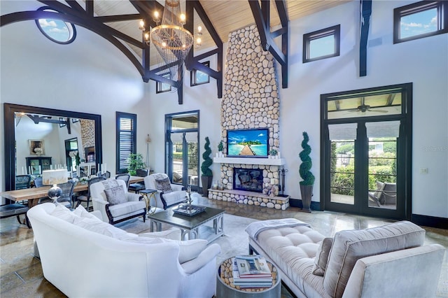 living room featuring a stone fireplace, a chandelier, french doors, and beamed ceiling