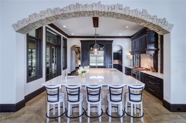 kitchen featuring sink, a center island with sink, a kitchen breakfast bar, stainless steel built in fridge, and pendant lighting