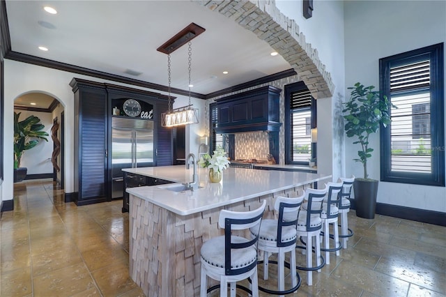 kitchen featuring decorative light fixtures, sink, a kitchen breakfast bar, built in refrigerator, and a center island with sink