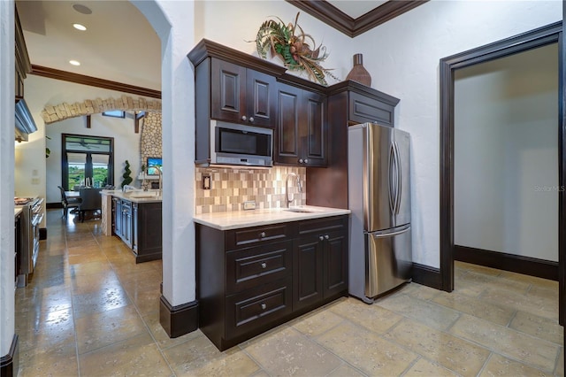 kitchen with dark brown cabinetry, backsplash, sink, and appliances with stainless steel finishes