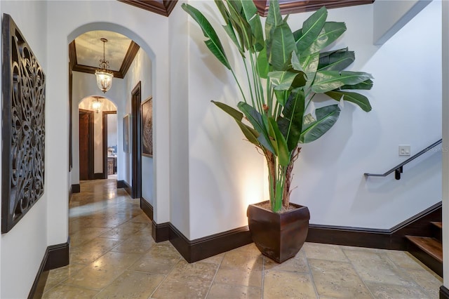 hallway with a notable chandelier and crown molding