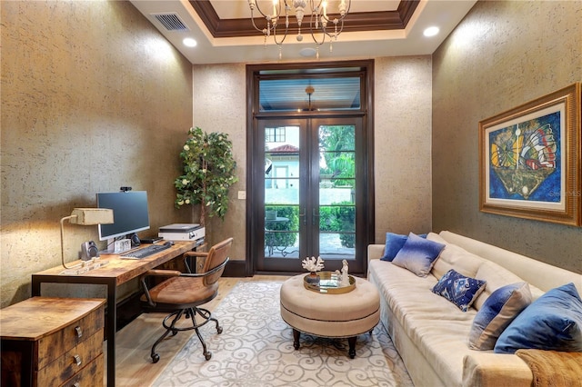 office space featuring ornamental molding, a notable chandelier, light hardwood / wood-style floors, a tray ceiling, and french doors