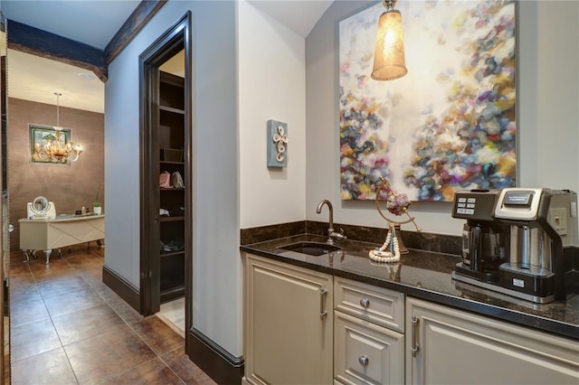 bar with sink, dark stone countertops, dark tile patterned floors, a notable chandelier, and pendant lighting