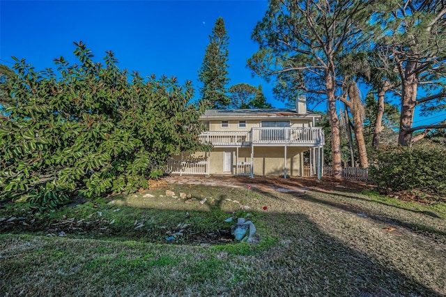 rear view of house featuring a wooden deck and a lawn