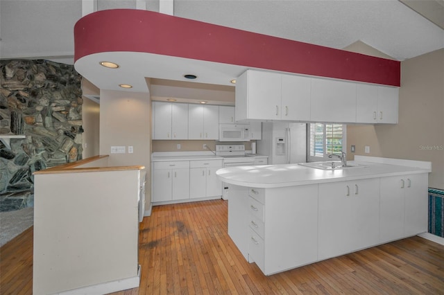 kitchen with sink, light wood-type flooring, kitchen peninsula, white appliances, and white cabinets