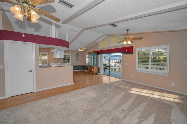 unfurnished living room featuring ceiling fan, lofted ceiling, light carpet, and a textured ceiling