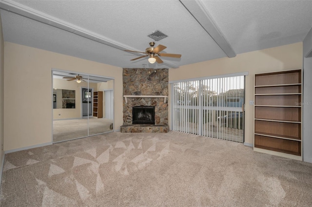 unfurnished living room with a stone fireplace, carpet flooring, and a textured ceiling