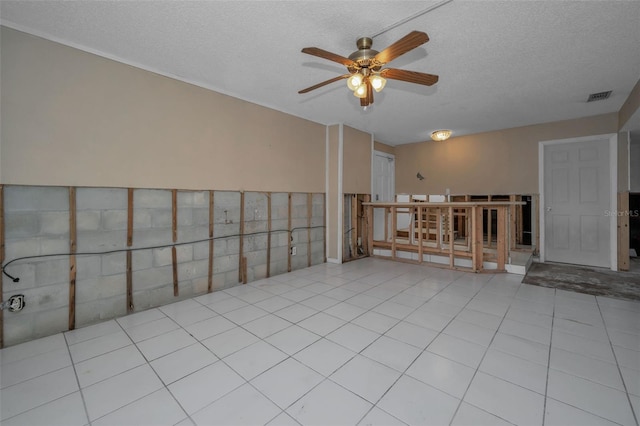 tiled empty room featuring ceiling fan and a textured ceiling