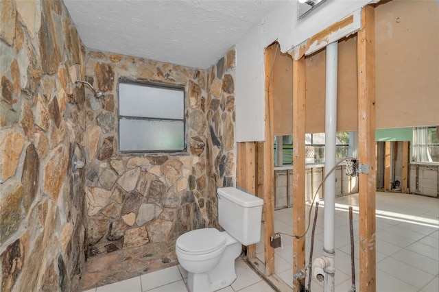 bathroom with toilet, tile patterned flooring, and a textured ceiling