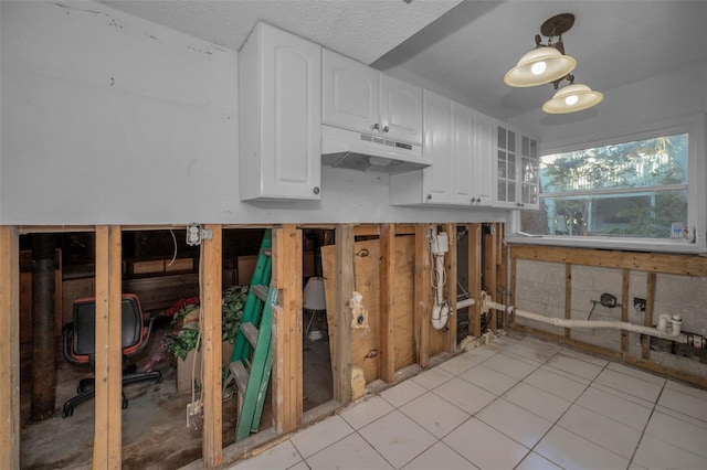 kitchen featuring white cabinetry, light tile patterned flooring, and a textured ceiling