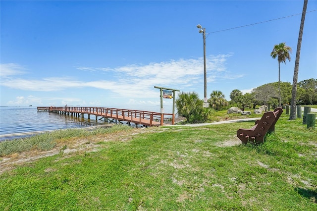 view of dock with a water view and a yard