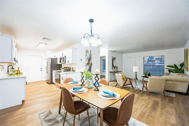 dining space with a chandelier and light wood-type flooring