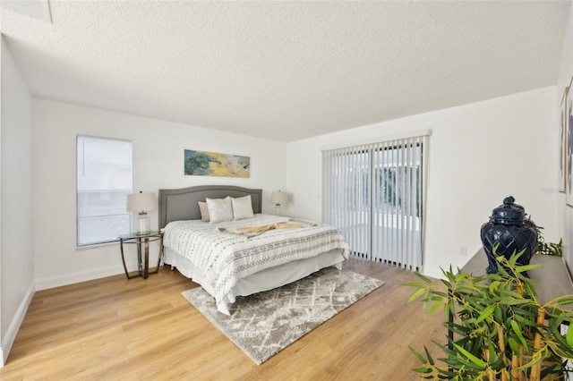 bedroom with hardwood / wood-style flooring, multiple windows, and a textured ceiling