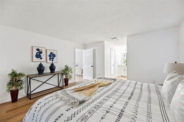 bedroom featuring hardwood / wood-style flooring, connected bathroom, and a textured ceiling