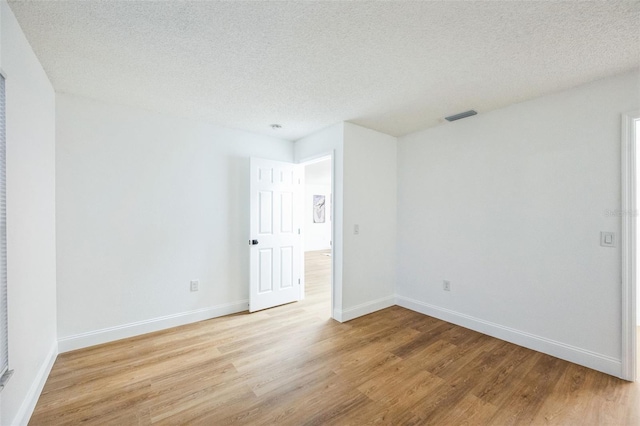 unfurnished room featuring light hardwood / wood-style flooring and a textured ceiling