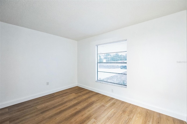 unfurnished room featuring wood-type flooring and a textured ceiling