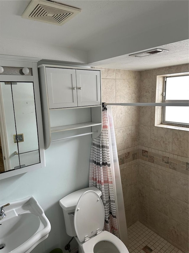 bathroom featuring toilet, curtained shower, sink, and a textured ceiling