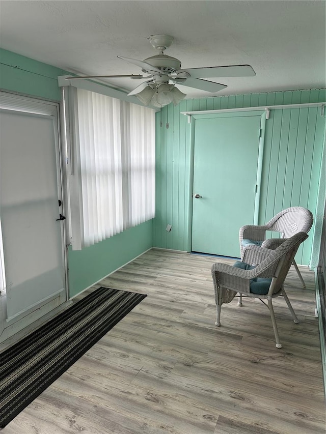 sitting room with ceiling fan and light wood-type flooring