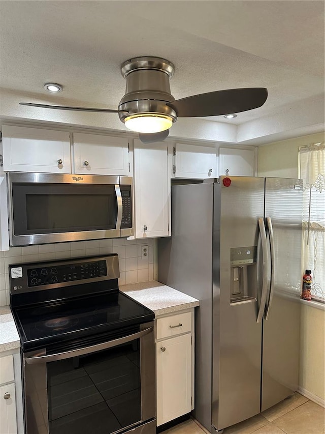 kitchen with white cabinetry, a textured ceiling, light tile patterned floors, appliances with stainless steel finishes, and backsplash