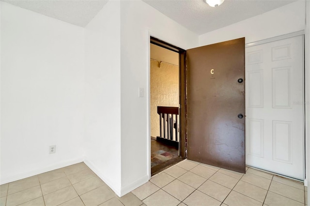 hallway featuring light tile patterned floors and a textured ceiling