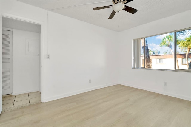 unfurnished room with ceiling fan, a textured ceiling, and light wood-type flooring