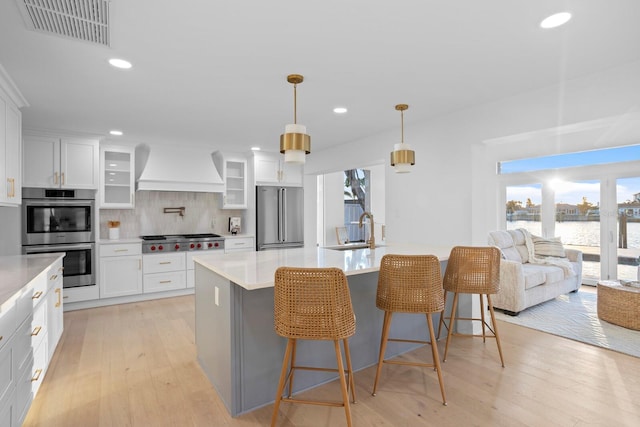 kitchen with stainless steel appliances, custom range hood, sink, and white cabinets