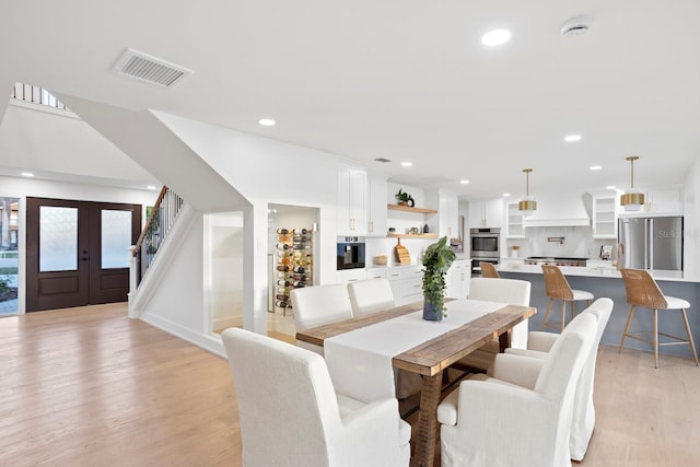 dining space featuring french doors and light wood-type flooring