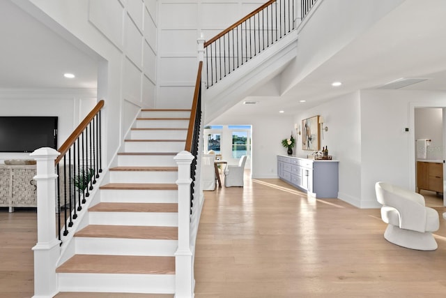 stairway with wood-type flooring and a towering ceiling