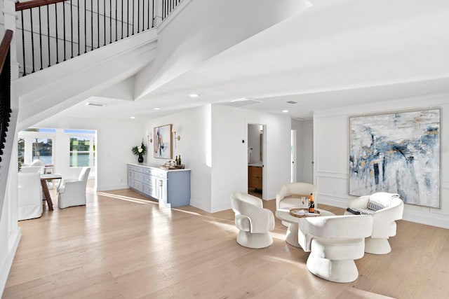 living area with a towering ceiling and light wood-type flooring