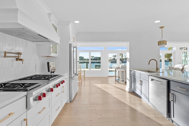 kitchen with custom exhaust hood, a water view, white cabinetry, pendant lighting, and stainless steel appliances