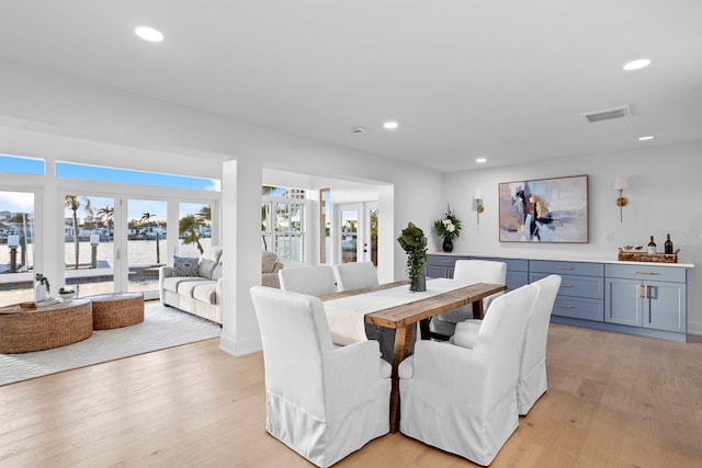 dining space featuring plenty of natural light, light hardwood / wood-style floors, and french doors