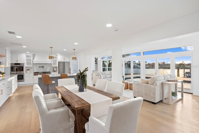 dining room with a water view and light hardwood / wood-style floors