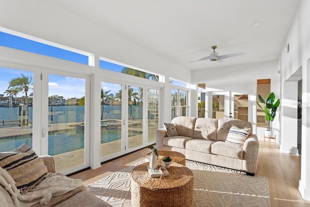 sunroom featuring ceiling fan and a water view