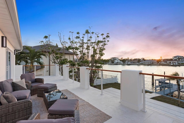 patio terrace at dusk featuring an outdoor hangout area, a balcony, and a water view