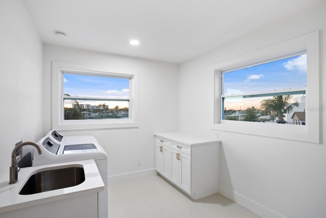 laundry room featuring washer and dryer, plenty of natural light, sink, and cabinets