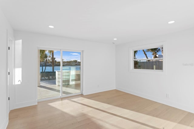 spare room with a water view and light hardwood / wood-style flooring