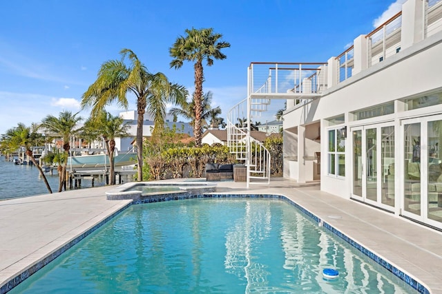 view of pool with an in ground hot tub, a water view, and a patio