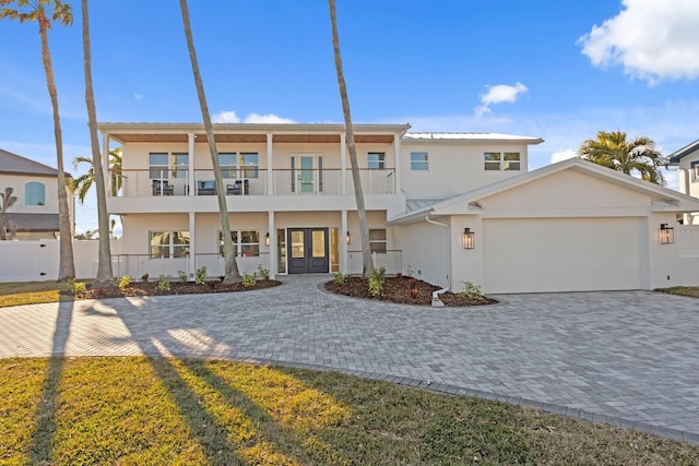 view of front of property featuring french doors, a balcony, and a garage