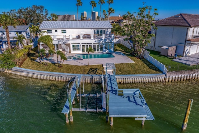 back of house featuring a fenced in pool, a patio area, a balcony, and a water view