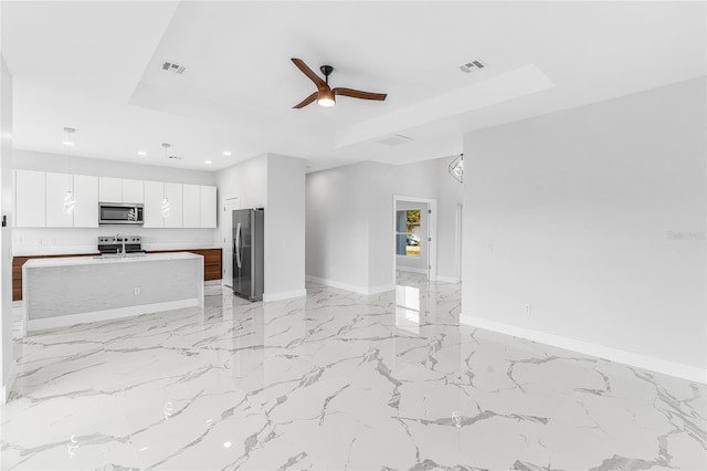 unfurnished living room with a raised ceiling and ceiling fan