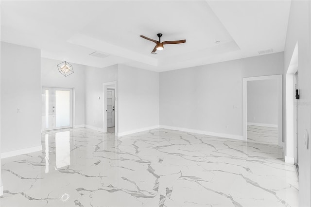 empty room featuring french doors, ceiling fan, and a raised ceiling