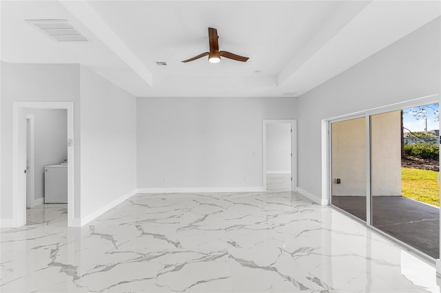 unfurnished bedroom featuring washer / clothes dryer, access to outside, ceiling fan, and a tray ceiling