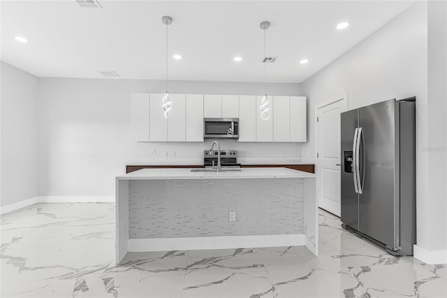 kitchen featuring sink, white cabinetry, hanging light fixtures, stainless steel appliances, and a center island with sink