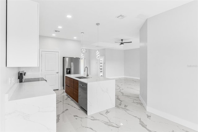 kitchen with pendant lighting, stainless steel appliances, light stone countertops, and a kitchen island with sink