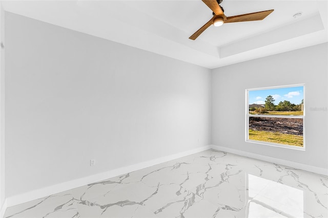 unfurnished room featuring a raised ceiling and ceiling fan