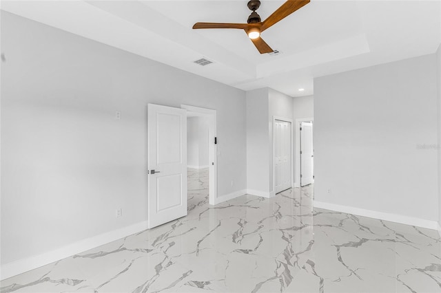 empty room with a raised ceiling and ceiling fan