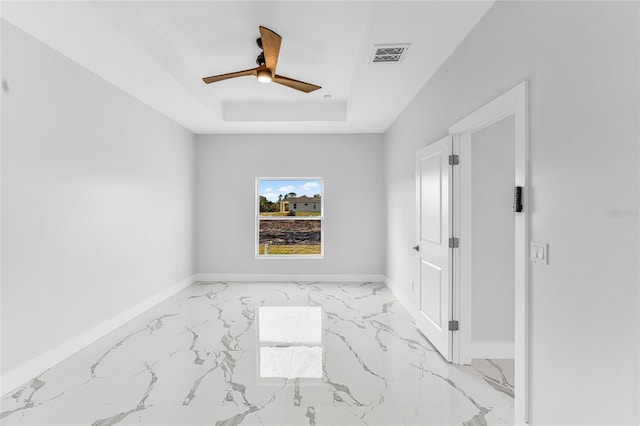 empty room featuring a raised ceiling and ceiling fan