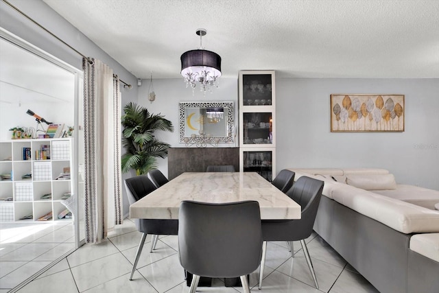 tiled dining area featuring an inviting chandelier and a textured ceiling