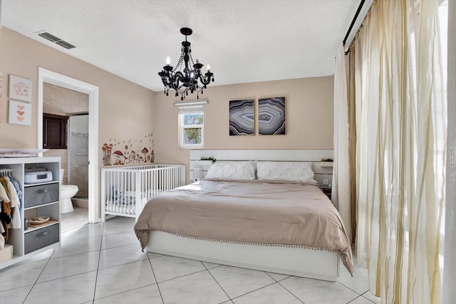 bedroom with connected bathroom, a chandelier, and a textured ceiling